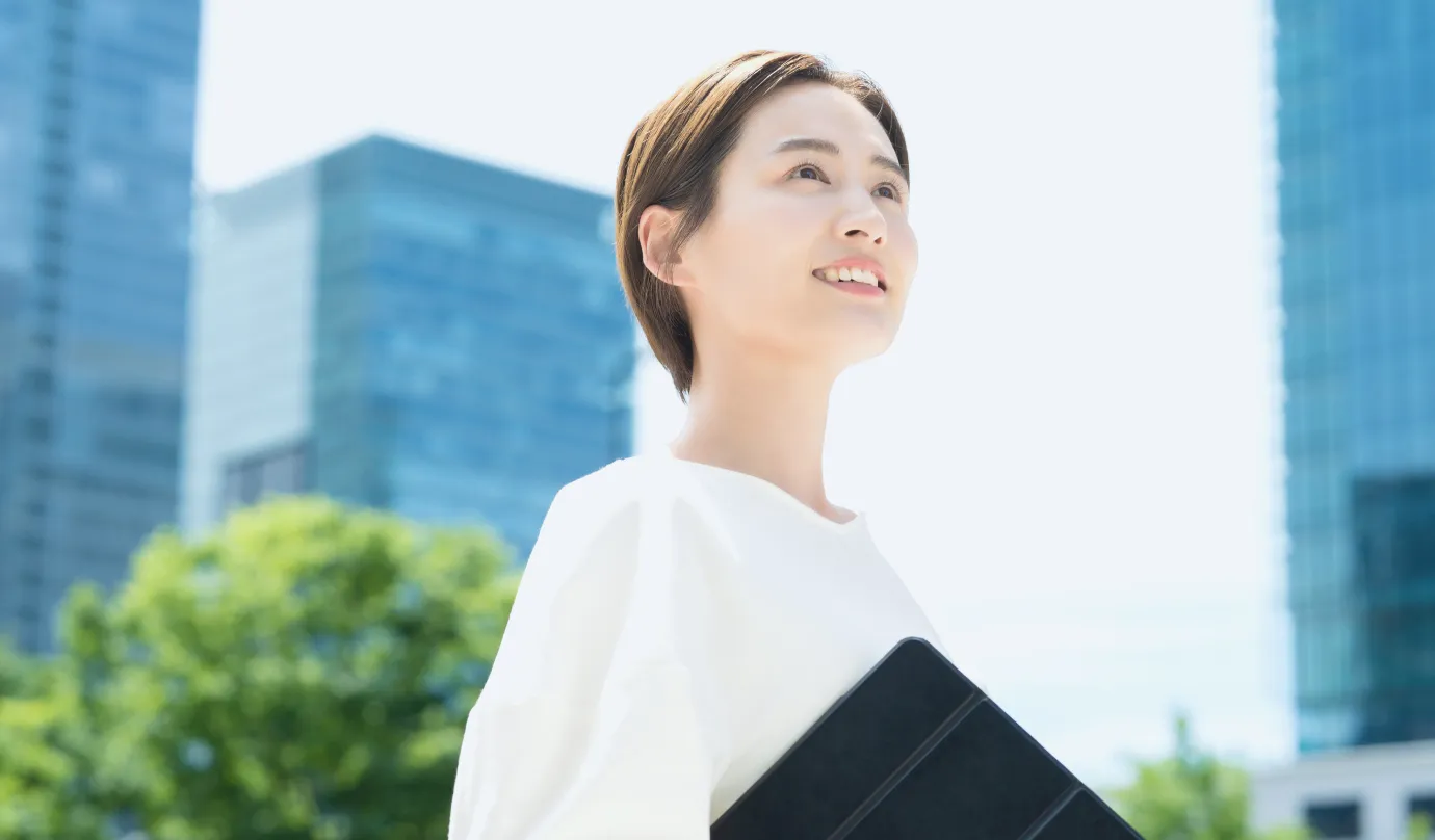 明るい日差しの中、笑顔で前を向く女性社員の写真