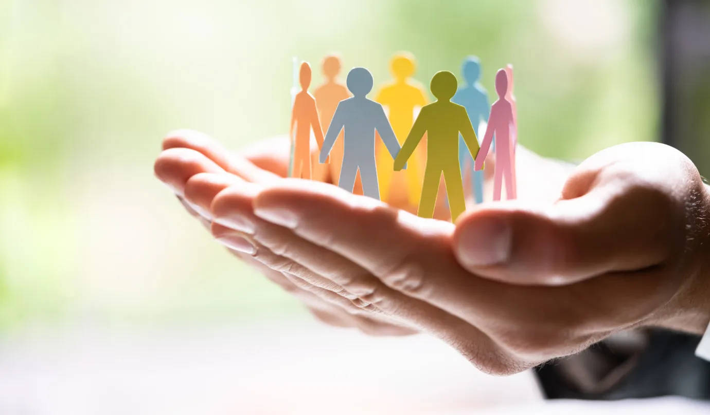 手のひらの上に並ぶカラフルな人型の紙のシルエット