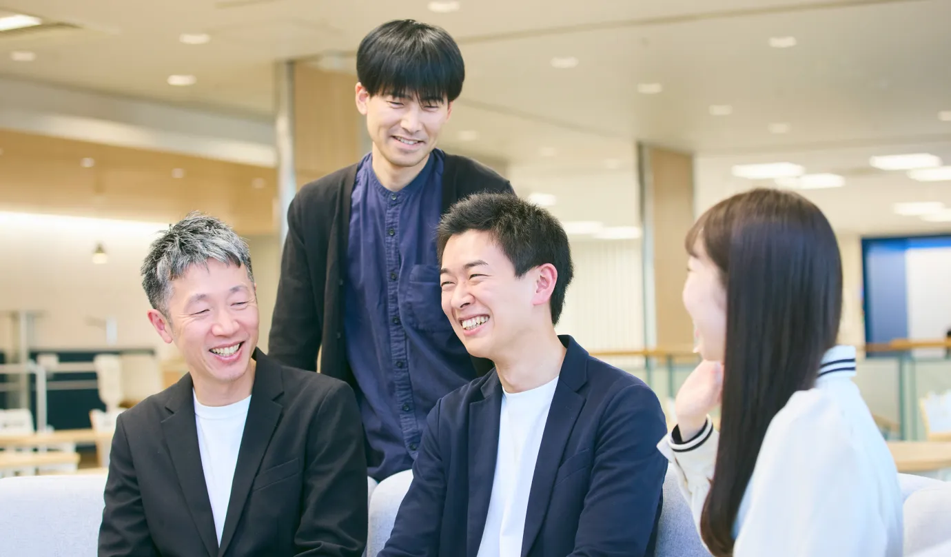 チームメンバーの男性社員3人と女性社員1人が談笑している写真