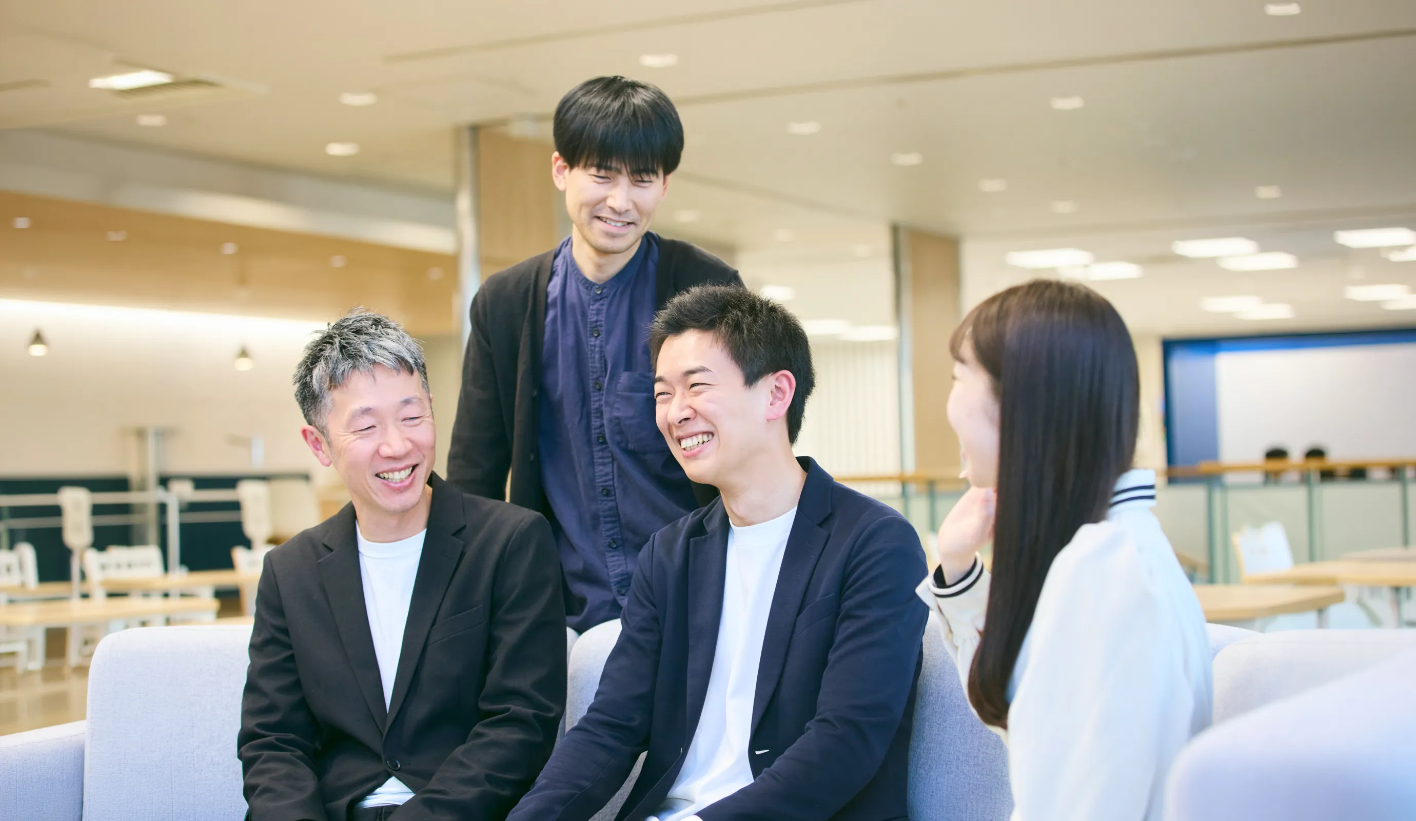 チームメンバーの男性社員3人と女性社員1人が談笑している写真