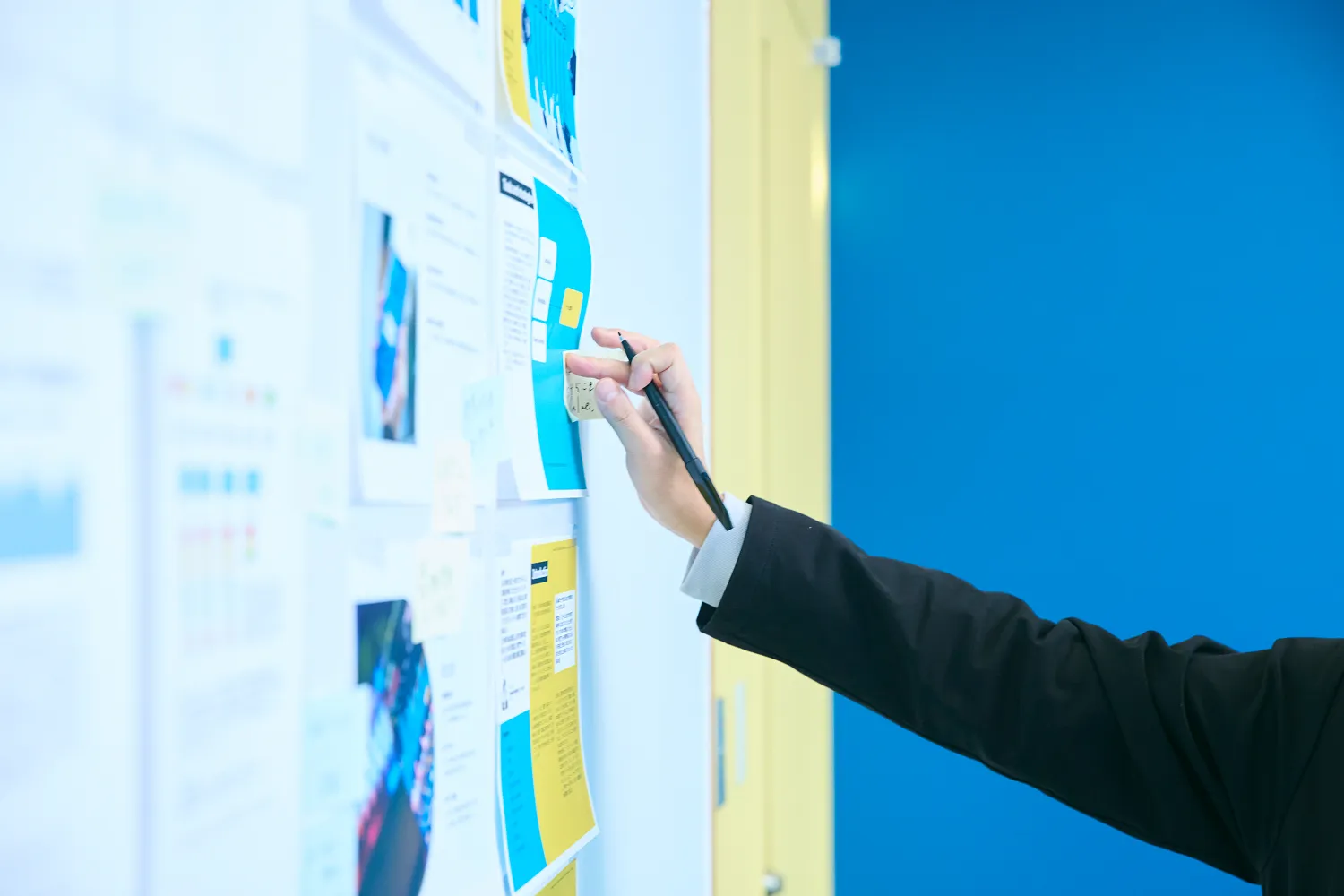 ホワイトボードに貼られた資料にペンで書き込もうとしている写真