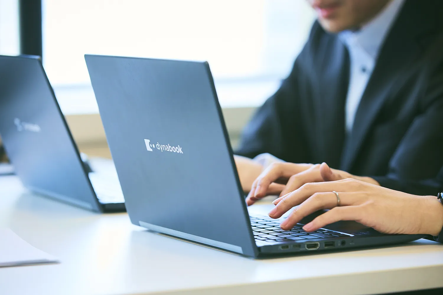 男性社員2人が机の上にならんだそれぞれPCをタイピングしている写真