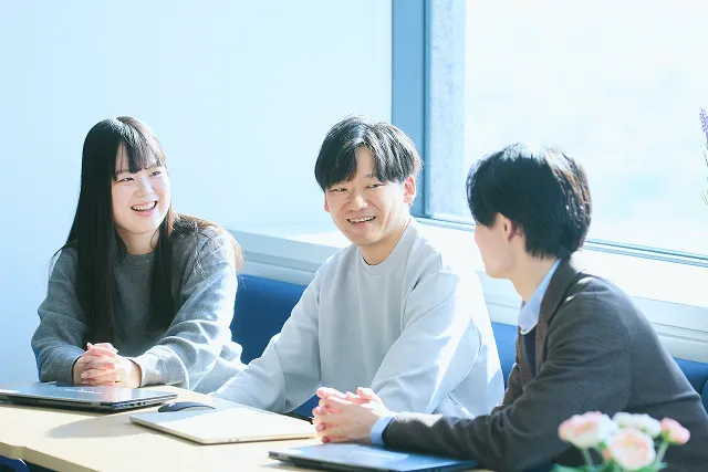 若手女性社員2人が、PCとタブレットを見ながら打ち合わせをしている写真。